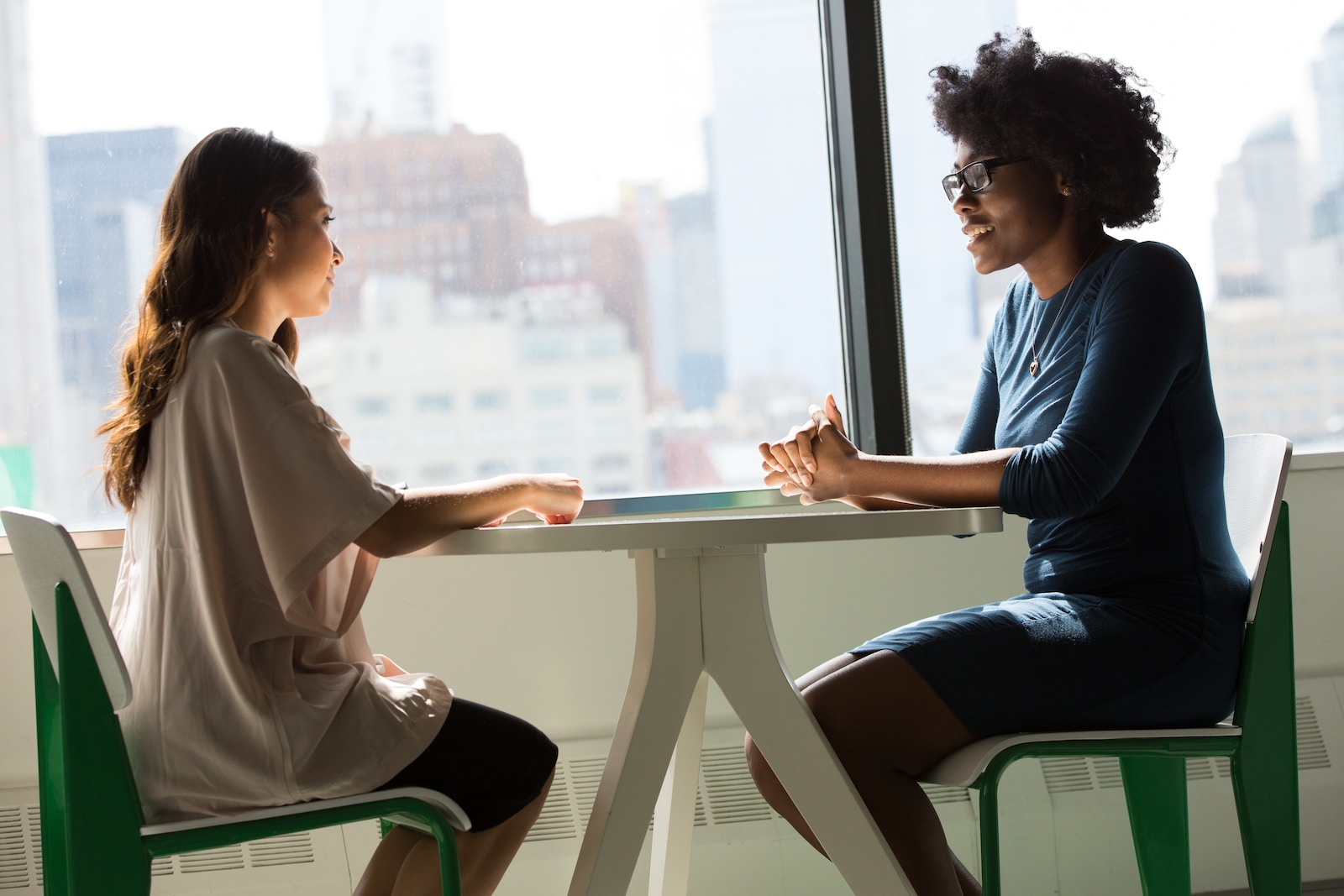 two women sitting beside table and talking